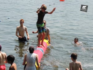 Campers play on the "Key-Log" during Open Waterfront, a time when campers can enjoy the beautiful weather, take out boats, or play in the swimming areas